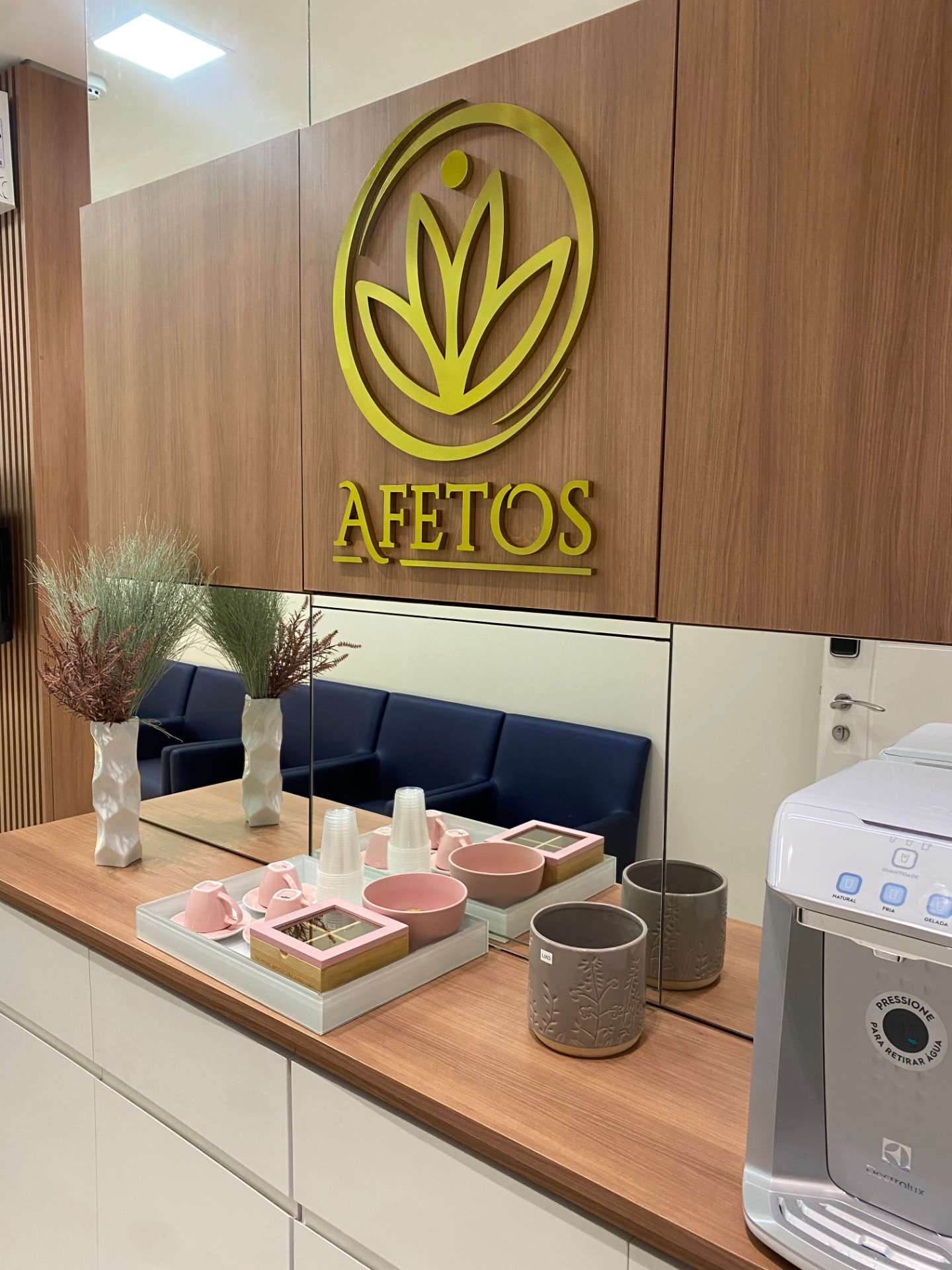 Logo da Afetos Clínica Médica em dourado no painel de madeira